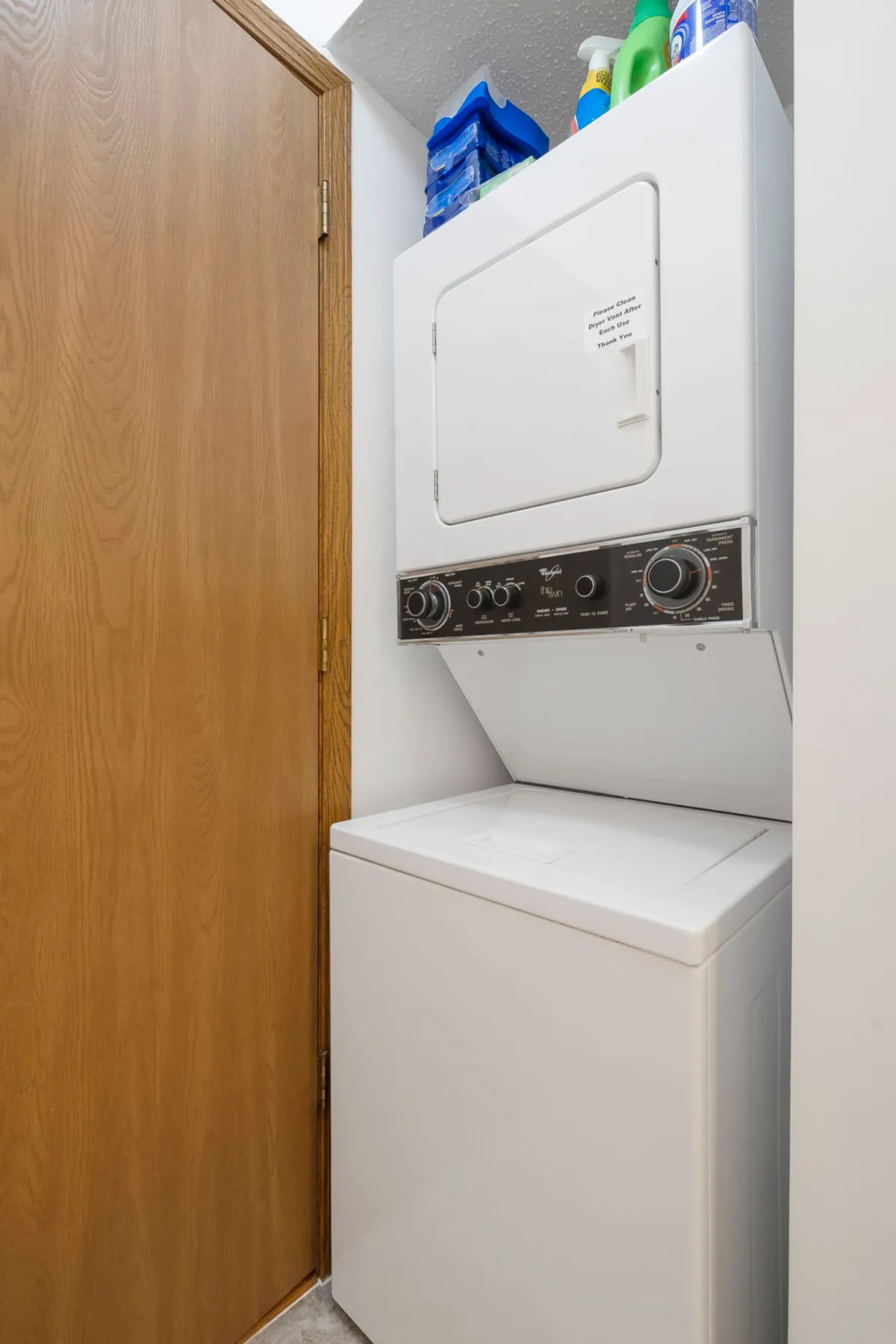 An in-unit washer and dryer are neatly tucked into a dedicated nook, with cleaning supplies placed on top. The space appears practical, clean, and user-friendly, emphasizing convenience for guests.