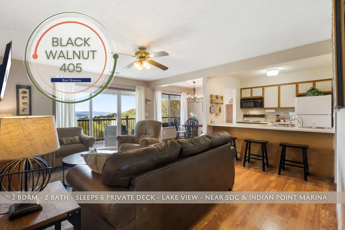 This image showcases a spacious open living area with a leather sofa, wooden dining table, expansive kitchen, and most importantly, large windows that reveal a sweeping view of Table Rock Lake. The abundant natural light and seamless flow between the living, dining, and kitchen spaces are on full display, capturing the core essence of the section.