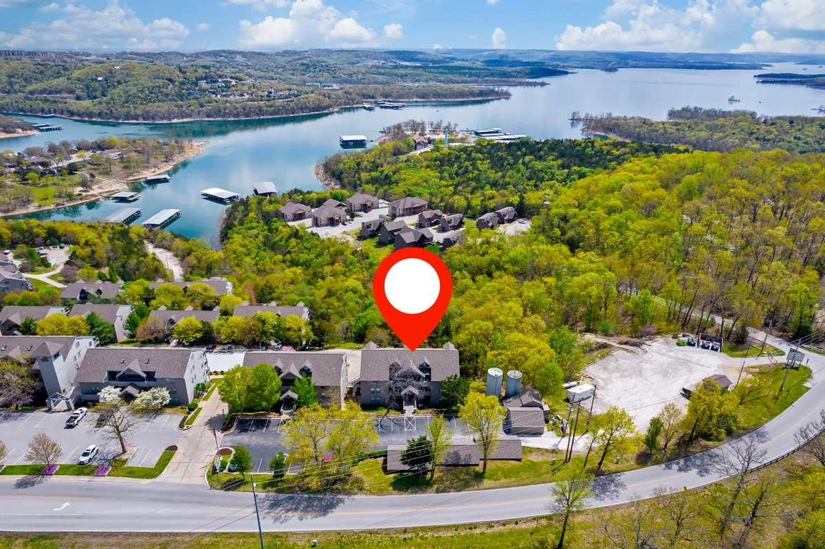A tranquil view of Table Rock Lake, complete with boats, green landscape, residential areas, and a winding road. The image captures the calm beauty of the lake and hints at the recreational opportunities available nearby, such as boating and relaxing by the water.
